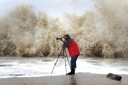 Man taking picture of crashing wave