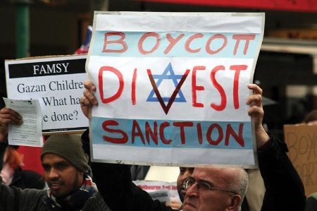 Man holding 'Boycott Divest Sanction' placard
