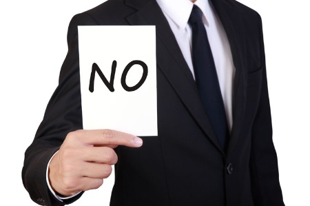 Businessman holding 'No' card