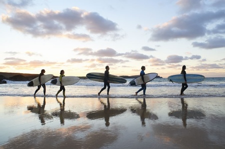 Surfers on beach carrying surfboards