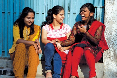 Three young women seated, chatting and laughing